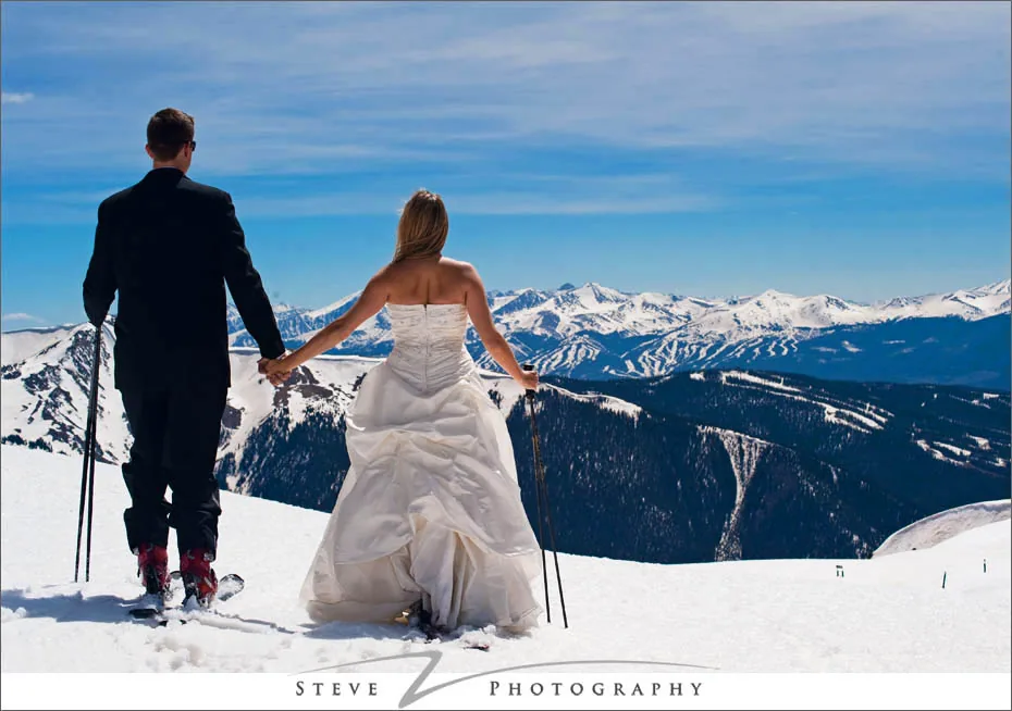 Wedding couple on skis overlooking the mountains
